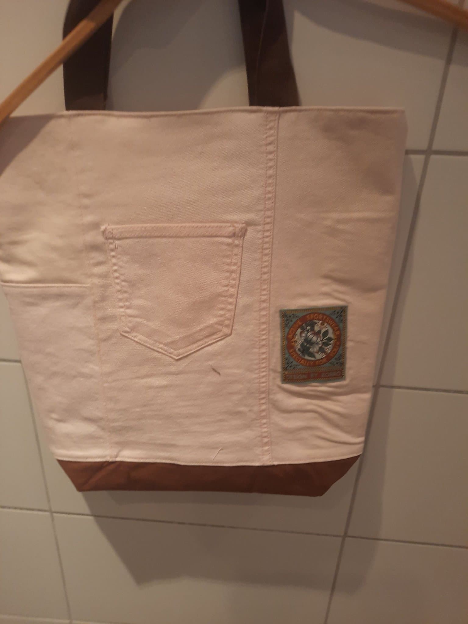 Kasse sydd av ljusrosa jeans, broderi och lakan, nysydd