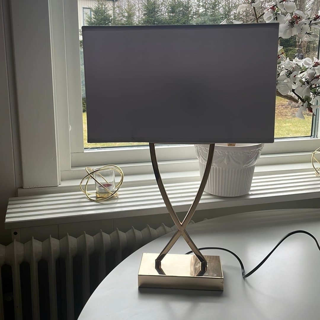 Bordslampa med guldfärgad fot och grå lampskärm