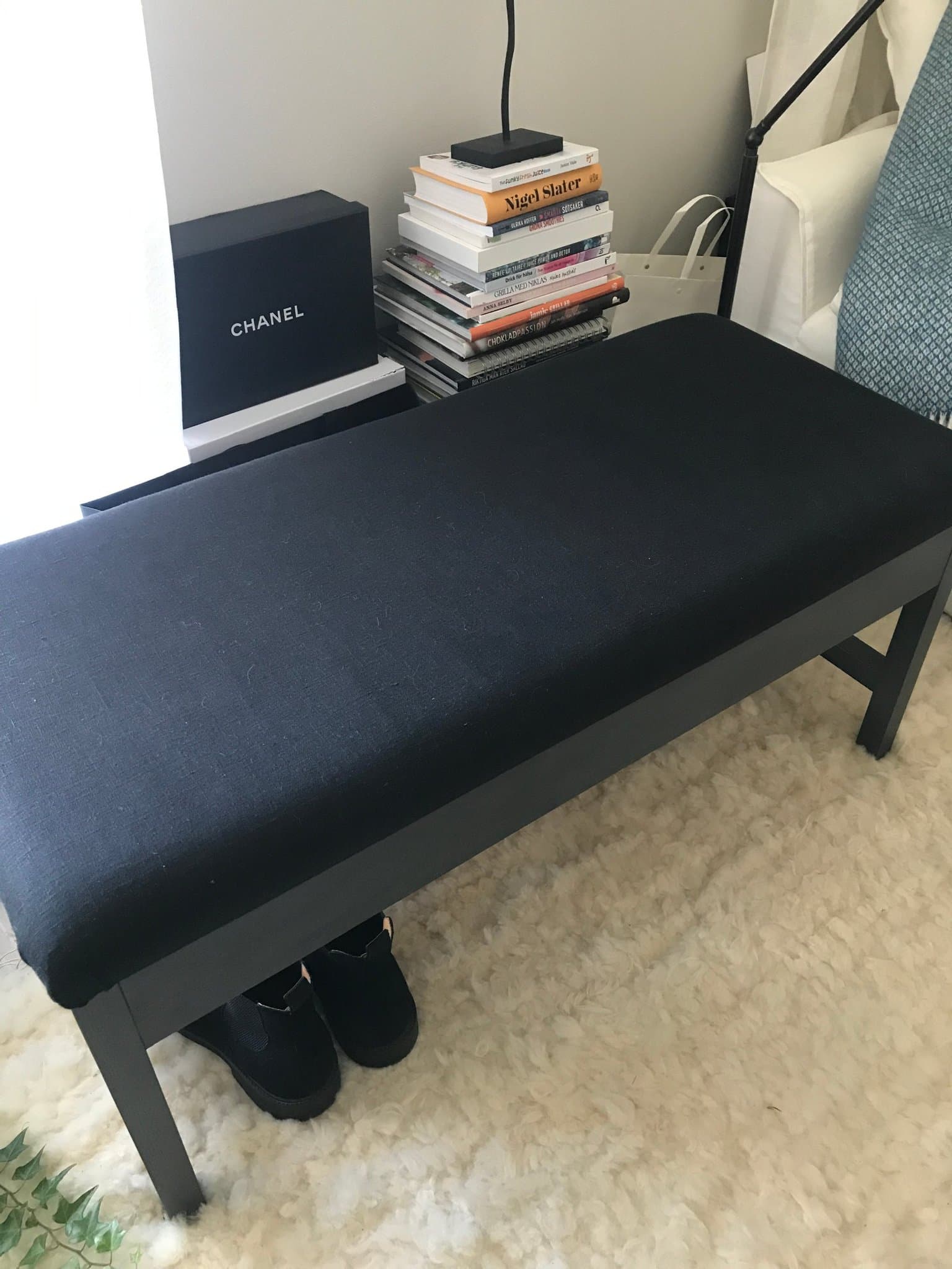 Stor svart förvaringsbänk i massivt trä, klädd i svart linne