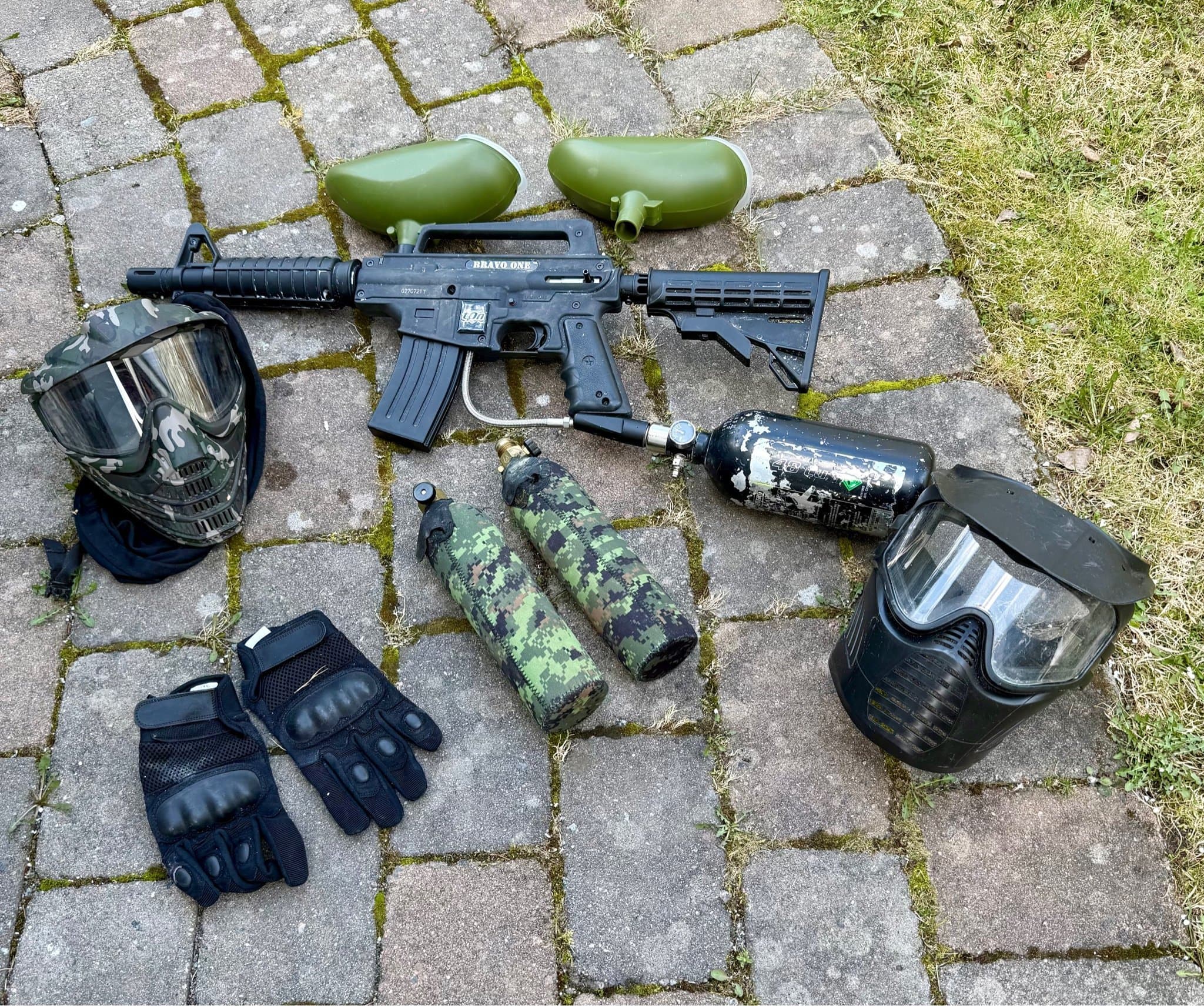 Paintballutrustning med markör, masker, tankar och handskar