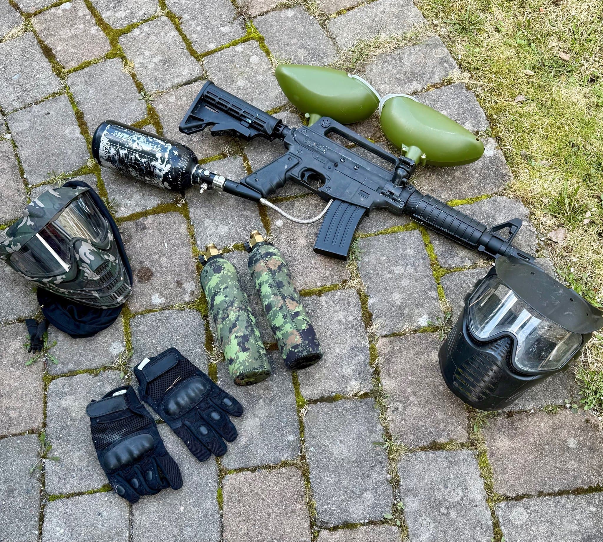 Paintballutrustning med markör, masker, tankar och handskar