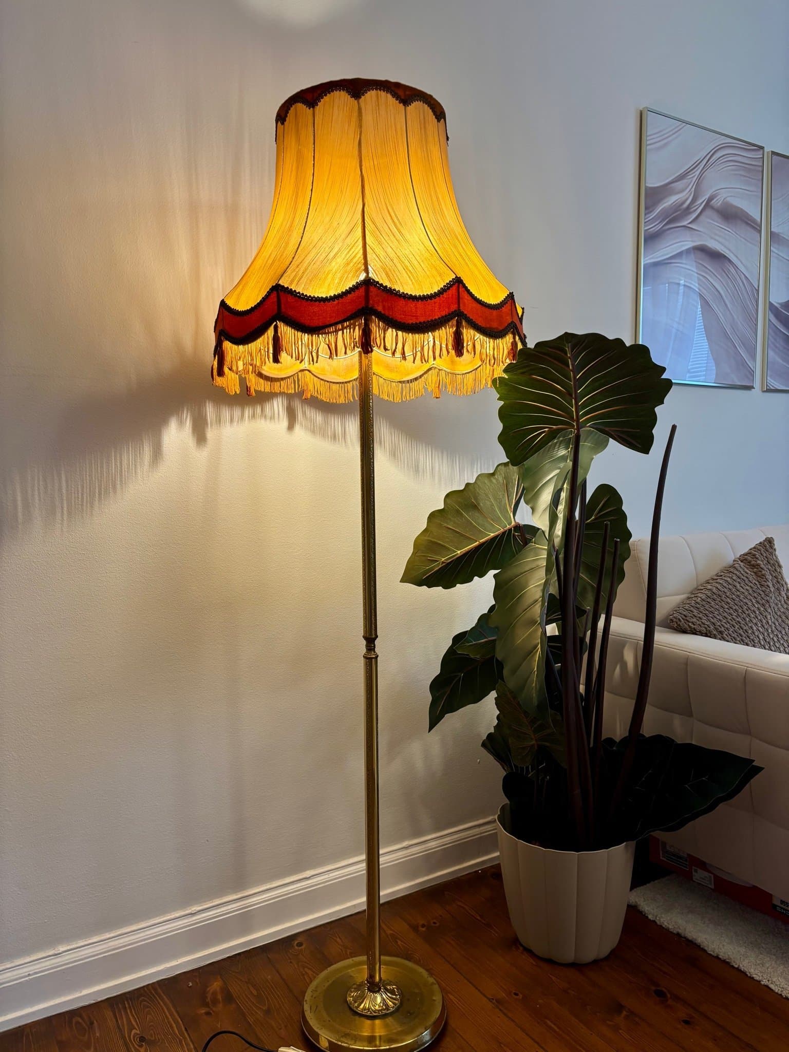 Golvlampa med guldfärgad stomme och gul lampskärm
