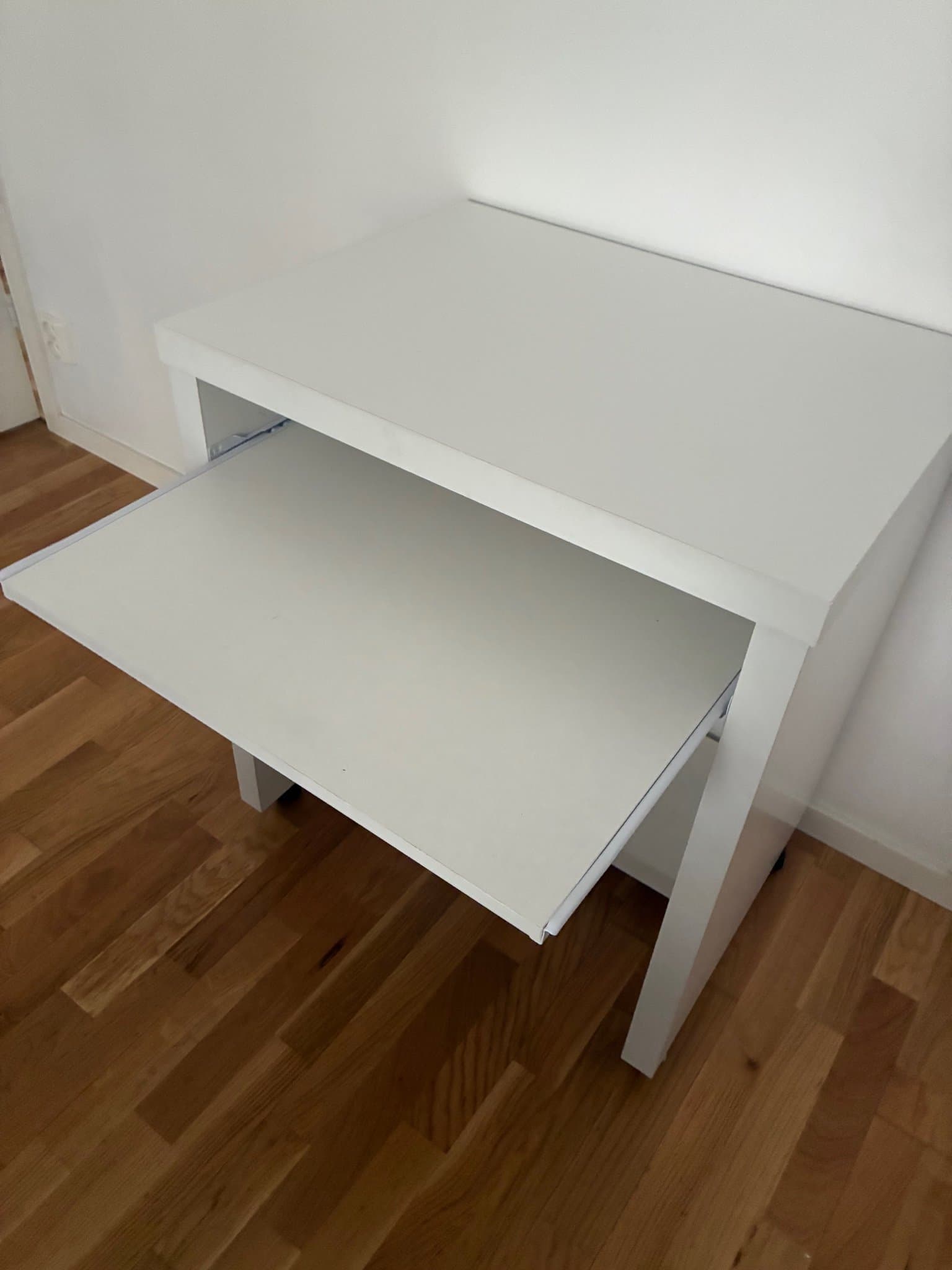 Vitt sängbord med utdragbar hylla och hjul