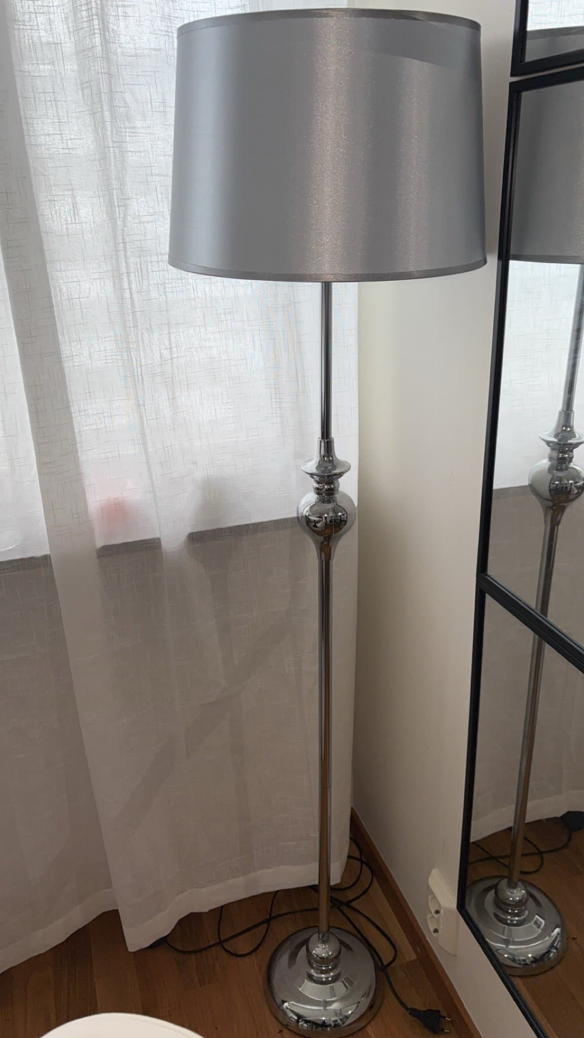 Golvlampa med silverfärgad skärm