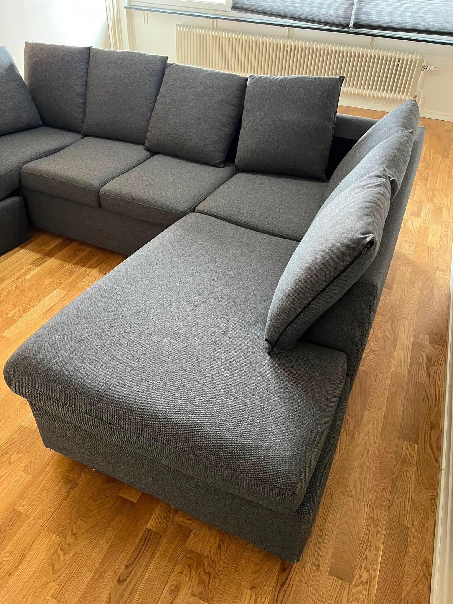 U-formad soffa i mörkgrått tyg med schäslong
