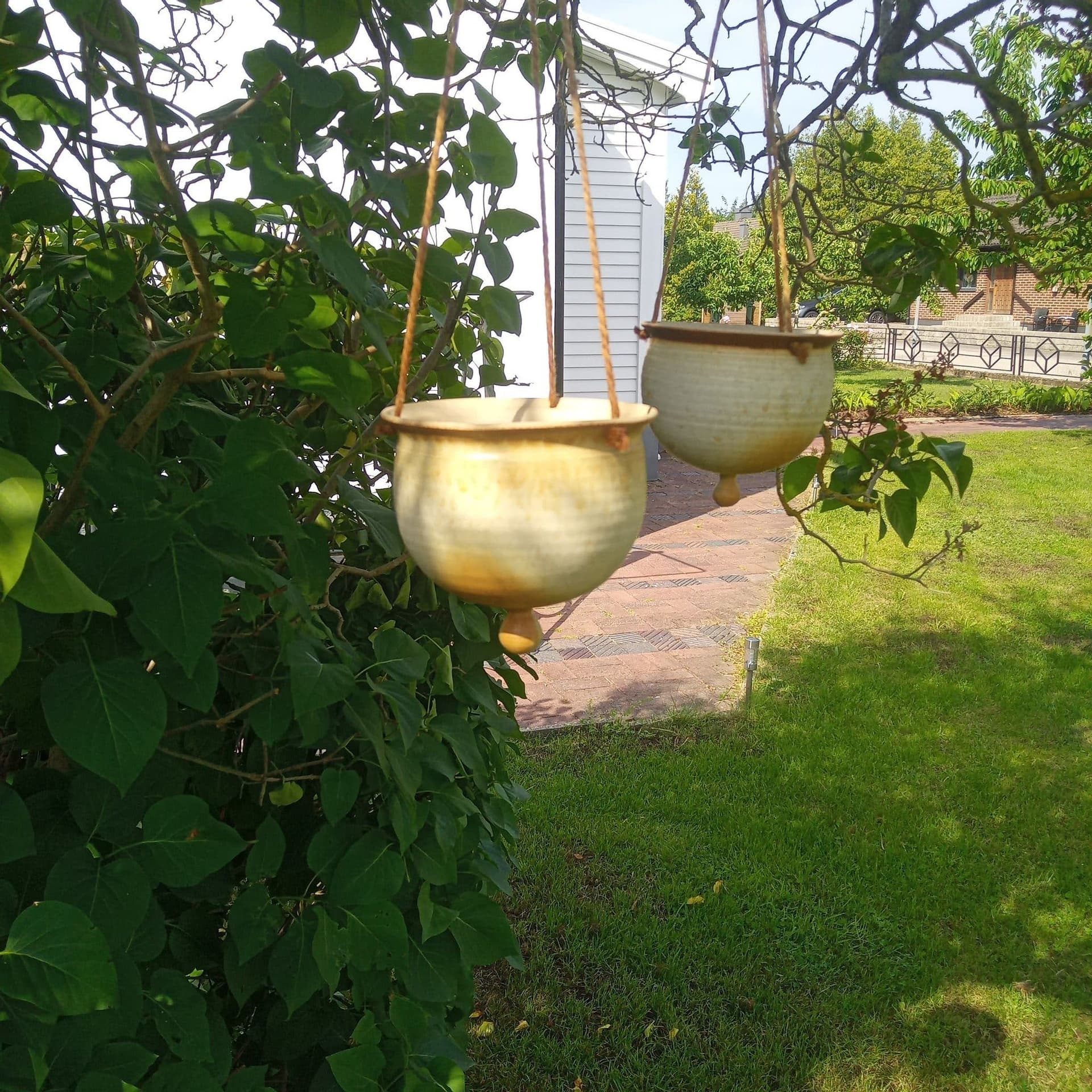 Två hängande krukor i keramik, amplar i gult, beige.